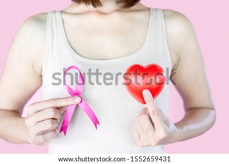 breast cancer concept with woman hand showing pink ribbon and heart 