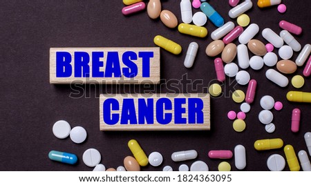BREAST CANCER is written on wooden blocks near multi-colored pills. Medical concept