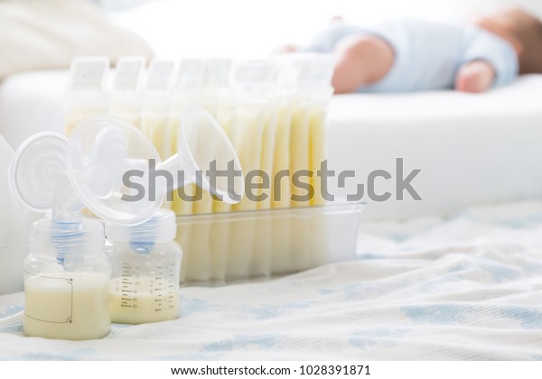 Breast milk frozen in storage bag and baby\
lying on background