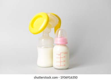 Breast pump and bottle of milk on grey background