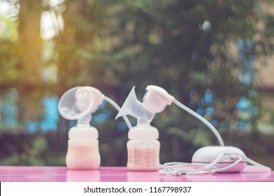 The breast pump on blurred nature background. Mothers breast milk is the most healthy food for newborn baby. The image of parenting. Composition with feeding bottle of baby milk formula on first week.