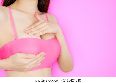 Breast Self-Exam (BSE). Beautiful Young Asian Woman Wearing Pink Bra or Lingerie Checking Her Breast on Pink Background. Sexy Female Screening, Cancer Prevention. Concept of Boob Augmentation.