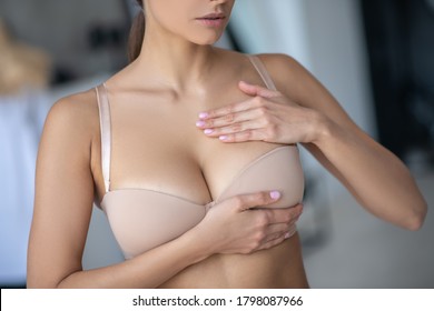 Breast. Woman in beige brassier examining her breast