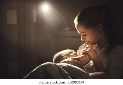 Breast-feeding. Mother Breastfeeds The Baby In The Dark In Bed
