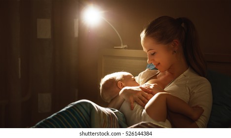 breastfeeding. mother feeding a baby breast in bed dark night