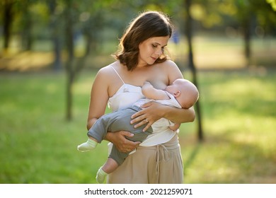 Breastfeeding On Public By Mother With Little Boy In Park.