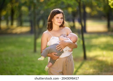 Breastfeeding In Public Park By Young Mother Outdoors.