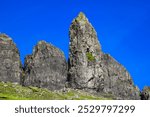 A breath taking, beautiful  landscape featuring rugged, grassy mountains and rocky hills on the Isle of Skye, Scotland. Unique rock formations stand out, creating an awe-inspiring natural view.