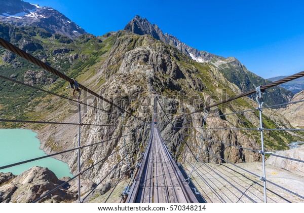 Breath taking view on the Trift beidge, a\
suspension bridge over the Triftsee, glacier, in Gimsel on Bernese\
Oberland, Switherland.