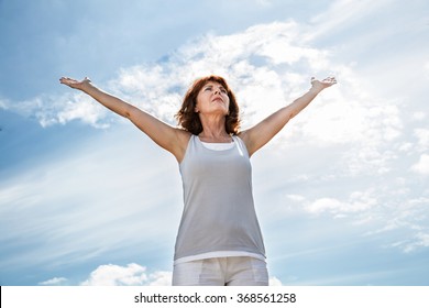 Breathing Outside - Older Yoga Woman Opening Up Her Arms To Exercise,practicing Meditation For Freedom Over Summer Blue Sky,low Angle View
