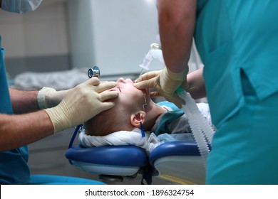 A Breathing Tube Is Inserted Into The Boy. Preparing For Surgery. The Child Is Under Anesthesia. Treatment Of Multiple Caries. Operation In The Dental Clinic. Side View.