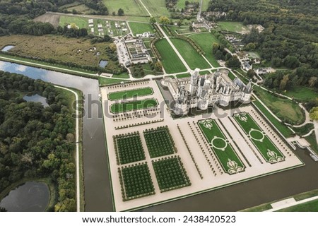 A breathtaking aerial view of the Chateau de Chambord, a grand castle surrounded by lush green trees, standing tall and regal in the midst of natures beauty