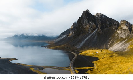 A breathtaking aerial view of a coastal mountain landscape. Steep, rocky cliffs rise sharply from the water, meeting with a winding road that skirts the shoreline. - Powered by Shutterstock