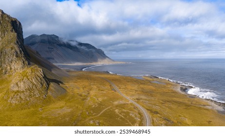 A breathtaking aerial view of a coastal mountain landscape. Steep, rocky cliffs rise sharply from the water, meeting with a winding road that skirts the shoreline. - Powered by Shutterstock