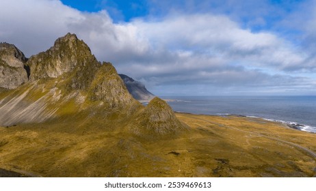 A breathtaking aerial view of a coastal mountain landscape. Steep, rocky cliffs rise sharply from the water, meeting with a winding road that skirts the shoreline. - Powered by Shutterstock