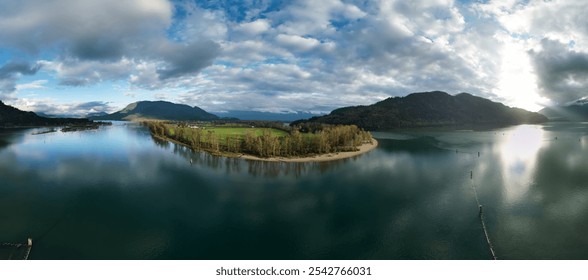 A breathtaking aerial view of Fraser Valley in British Columbia, Canada, showcasing a serene river, lush greenery, and distant mountains under a cloudy sky. - Powered by Shutterstock