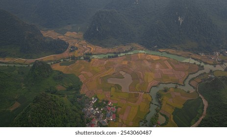 A breathtaking aerial view of a lush green valley surrounded by towering mountains. A winding river cuts through the serene landscape under a clear, expansive sky, creating a sense of natural beauty - Powered by Shutterstock