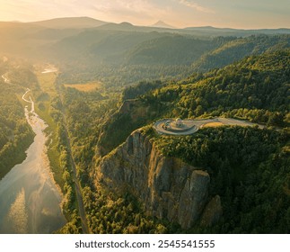 A breathtaking aerial view of a lush green valley at sunrise, featuring a scenic overlook and a winding river meandering through the vibrant landscape, creating a peaceful and serene atmosphere. - Powered by Shutterstock