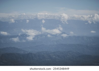 A breathtaking aerial view of a misty mountain landscape. Rolling hills and valleys stretch into the distance, punctuated by fluffy clouds. The scene evokes a sense of tranquility and wonder. - Powered by Shutterstock