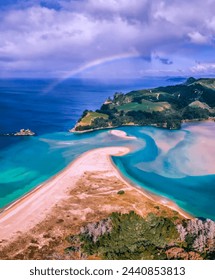 Breathtaking Aerial View of a Pristine Coastal Paradise, Featuring a Vivid Rainbow Arching Over Emerald Green Hills, Crystal Clear Turquoise Waters, and a Serene White Sandbar Stretching into the Ocea
