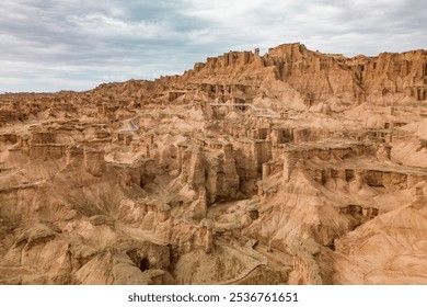 A breathtaking aerial view of a rugged desert canyon landscape at golden hour, showcasing dramatic rock formations, sandy terrain, and a winding road under a clear sky - Powered by Shutterstock