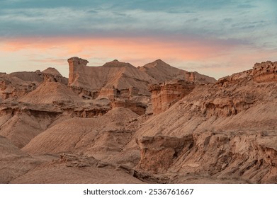 A breathtaking aerial view of a rugged desert canyon landscape at golden hour, showcasing dramatic rock formations, sandy terrain, and a winding road under a clear sky - Powered by Shutterstock