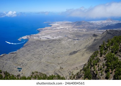 A breathtaking aerial view of the rugged landscape and coastal area in Tamadaba Natural Park, featuring rocky terrain, lush forests, and expansive ocean views. - Powered by Shutterstock