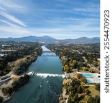 A breathtaking aerial view of the Sacramento River, framed by lush greenery, bridges, and a vibrant recreational area with mountains in the distance. Perfect for travel or nature photography