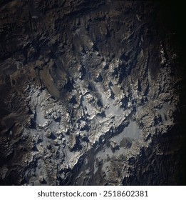 A breathtaking aerial view of a snowcapped mountain range under a dark, starry sky. The landscape is illuminated by the electric blue glow of the aurora . Elements of this image furnished by NASA - Powered by Shutterstock