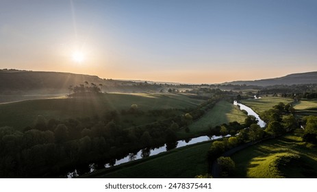 A breathtaking aerial view of a sunrise casting golden light over the river and valley landscape of Hawes, situated in the Yorkshire Dales of the UK - Powered by Shutterstock