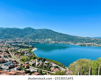 A breathtaking aerial view of a tranquil Italian lakeside town surrounded by lush greenery and majestic mountains. The serene blue water, vibrant landscape - Powered by Shutterstock