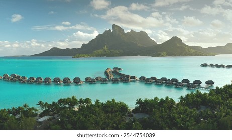 Breathtaking aerial view of turquoise lagoon, palm trees beach, overwater bungalows resort on tropical Bora Bora island. Green mountain sunset light. Popular tourist destination, exotic summer travel - Powered by Shutterstock