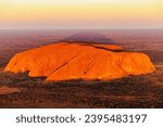 A breathtaking aerial view of Uluru Rock in Australia illuminated by a stunning sunset