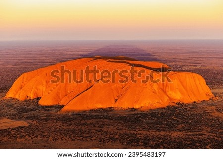 A breathtaking aerial view of Uluru Rock in Australia illuminated by a stunning sunset