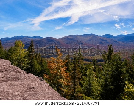Breathtaking beauty of the Adirondack Mountains in New York State, where the landscape comes alive with the vibrant hues of fall colors against the backdrop of a stunning sky.