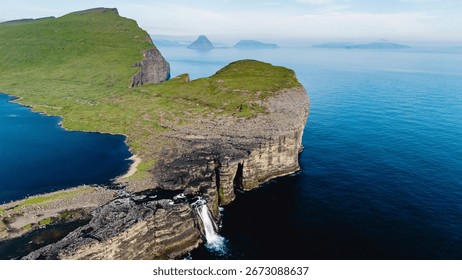 Breathtaking cliffs rise dramatically above calm waters in the Faroe Islands, adorned with cascading waterfalls. The scene captures the tranquility and natural beauty found in this remote paradise.