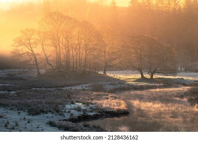 Breathtaking Golden Light Illuminating Frosty Winter Landscape With Misty River Near Elterwater In The Lake District, UK.