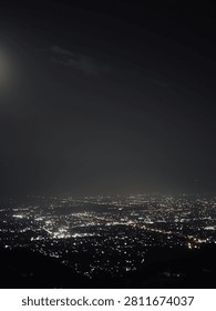 Breathtaking high angle panoramic night view of a sprawling city lit up under a dark night sky.