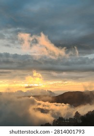A breathtaking high-angle landscape showcasing a dramatic golden sunrise over a thick sea of clouds and rolling mist covering the mountains and forests of Shimla.