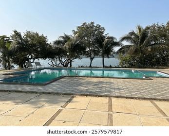 A breathtaking infinity pool seamlessly blending into the horizon, with a calm river flowing in the background. Towering trees surround the scene, creating a peaceful and luxurious nature retreat. 