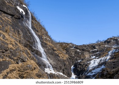 The breathtaking Kjosfossen waterfall cascades down a rocky cliff face. Surrounded by lush greenery and snow-capped mountains, this natural wonder is a popular tourist attraction. Norway. - Powered by Shutterstock