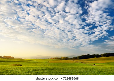 Breathtaking lansdcape of Austrian countryside on sunset. Dramatic sky over idyllic green fields of Anstrian Central Alps on early autumn evening.