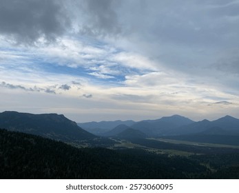A breathtaking mountain range under a cloudy sky, with layers of peaks, lush green valleys, and distant ridges creating a serene and majestic landscape.