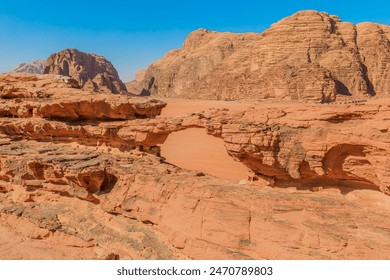 Breathtaking natural rock arch, known as Little bridge stands resilient amidst the stunning red sands, and rugged mountains of the iconic Wadi Rum desert in Jordan - Powered by Shutterstock