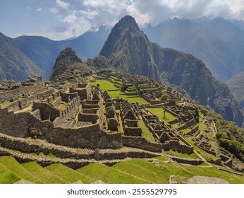 A breathtaking panoramic view of Machu Picchu, showcasing ancient terraces, stone ruins, and surrounding mountains under a cloudy sky