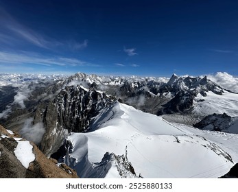 A breathtaking panoramic view of mountains, partially covered with snow, seen from above. The clear blue sky complements the landscape, highlighting the majesty and beauty of nature. - Powered by Shutterstock