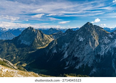 A breathtaking panoramic view of rugged alpine summits bathed in golden autumn light during a serene hiking journey through the Tannheimer Valleys scenic trails