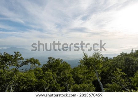 A breathtaking panoramic view from the summit of Mount Fuji, Japan's highest and most iconic volcano. The image captures the rugged volcanic crater, rocky ridges, winding hiking trails, and dramatic landscape above the clouds beneath a brilliant blue sky. This spectacular scene showcases the natural beauty and geological significance of Mount Fuji, a UNESCO World Heritage Site and one of Japan's most famous travel destinations. Ideal for themes of adventure, hiking, volcanic landscapes, nature, travel, and outdoor exploration.