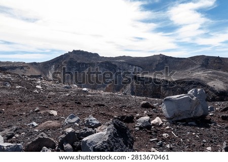 A breathtaking panoramic view from the summit of Mount Fuji, Japan's highest and most iconic volcano. The image captures the rugged volcanic crater, rocky ridges, winding hiking trails, and dramatic landscape above the clouds beneath a brilliant blue sky. This spectacular scene showcases the natural beauty and geological significance of Mount Fuji, a UNESCO World Heritage Site and one of Japan's most famous travel destinations. Ideal for themes of adventure, hiking, volcanic landscapes, nature, travel, and outdoor exploration.