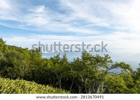 A breathtaking panoramic view from the summit of Mount Fuji, Japan's highest and most iconic volcano. The image captures the rugged volcanic crater, rocky ridges, winding hiking trails, and dramatic landscape above the clouds beneath a brilliant blue sky. This spectacular scene showcases the natural beauty and geological significance of Mount Fuji, a UNESCO World Heritage Site and one of Japan's most famous travel destinations. Ideal for themes of adventure, hiking, volcanic landscapes, nature, travel, and outdoor exploration.